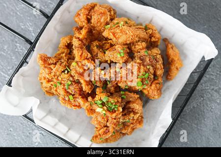 Vue de dessus des morceaux de poulet Ganjang (poulet frit à l'ail-soja coréen), garni d'échalotes hachées. Banque D'Images