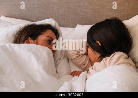 Deux femmes dorment dans un lit avec l'une d'elles ayant la tête sous l'autre. La scène est paisible et intime Banque D'Images