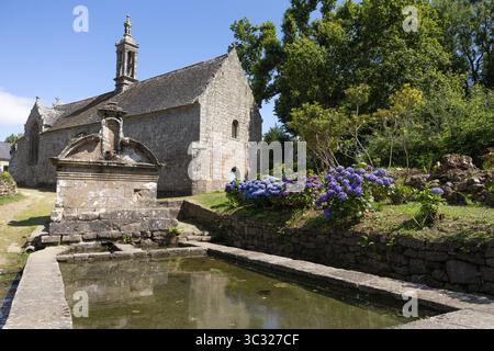 La chapelle notre Dame de bonne Nouvelle du XVème siècle se reflète dans le lavoir devant la fontaine Saint Eutrope à Locronan, Bretagne, France. Banque D'Images