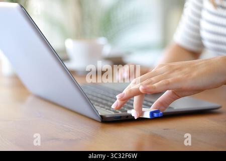 Gros plan d'une main de femme branchant le lecteur de stylo sur l'ordinateur portable Banque D'Images
