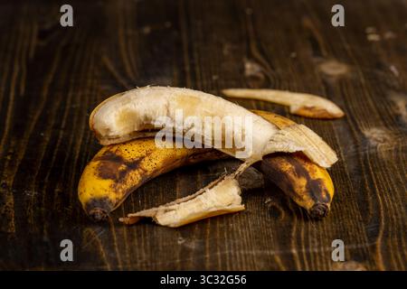 vieille banane noircie pendant le stockage sur une planche de pin noir, banane pourrie noircie sur une table en bois Banque D'Images