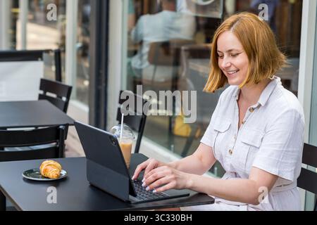 Femme travaillant sur ordinateur portable, assise dans un café moderne Banque D'Images