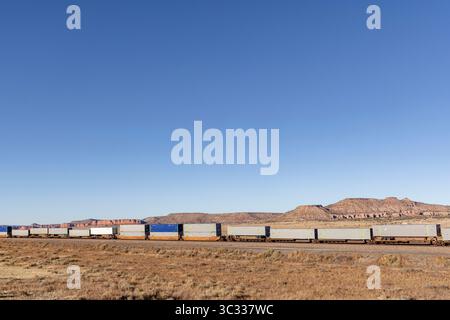 Le train intermodal américain traverse un environnement désertique Banque D'Images
