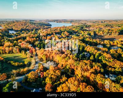 Vue aérienne de la ville boisée en automne de pointe avec des lacs en arrière-plan Banque D'Images