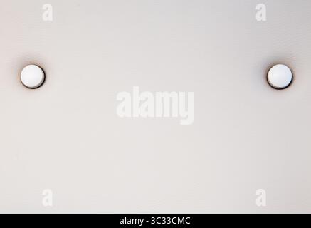 Texture de la sellerie en cuir blanc d'une chaise avec des boutons, gros plan. Fond en cuir blanc. Banque D'Images