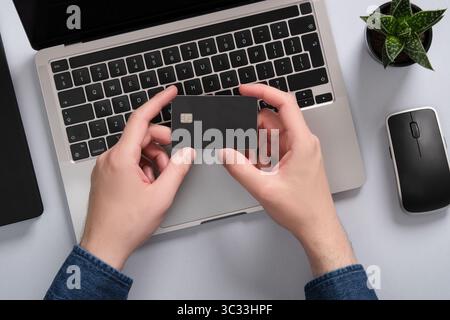 Un homme tient une carte bancaire à deux mains. Paiements en ligne avec une carte de crédit. Banque D'Images