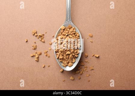 Cuillère avec café instantané granulé sur fond beige, vue de dessus Banque D'Images