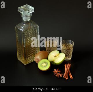 Kiwi maison et liqueur de pomme verte avec cannelle et anis sur fond noir. Gros plan. Banque D'Images