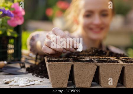 Gros plan de femme semant des graines dans des pots biodégradables, en commençant des plantes de jardin pour une croissance printanière saine Banque D'Images