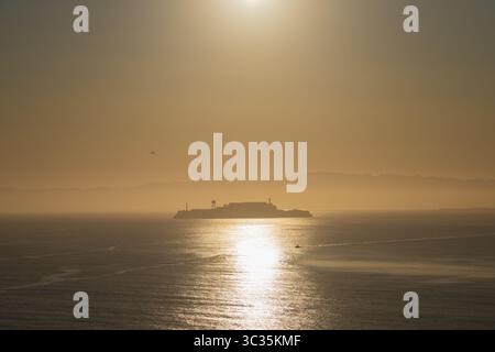 Île d'Alcatraz dans la baie de San Francisco, au lever du soleil, avec teinte orange et jaune Banque D'Images