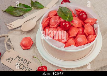 Boulettes de cerises congelées dans un bol en papier, composition plate avec des cerises fraîches, menthe, étiquette faite à la main. Concept zéro déchet de livraison de nourriture, SMART co Banque D'Images