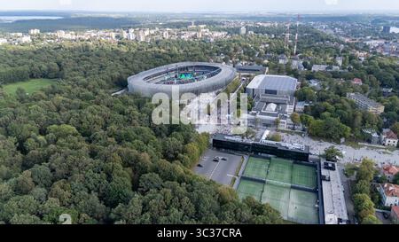 Vue aérienne d'un stade moderne entouré de verdure luxuriante, avec des bâtiments urbains en arrière-plan. La scène capture une atmosphère vibrante avec peop Banque D'Images