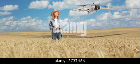 Agricultrice volant un drone au-dessus d'un champ de blé, concept de technologie moderne de l'agriculture Banque D'Images