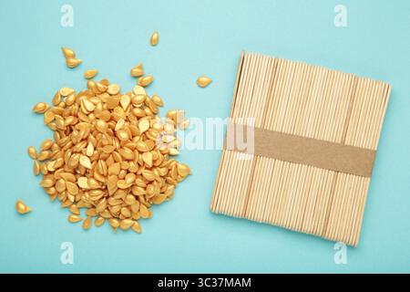 Beaux granules de cire épilatoire dorée et spatules en bois sur fond bleu. Épilation, épilation, épilation indésirable. Vue de dessus Banque D'Images