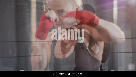 Boxer de protection dans le débardeur levant les poings dans l'anneau de boxe, avec des enveloppes rouges et des gants noirs Banque D'Images
