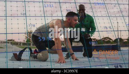 Coureur amputé accroupi utilisant une lame au niveau des blocs sur la piste, avec entraîneur utilisant un dispositif superposant le danger Banque D'Images