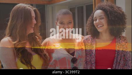 Souriant trois amis debout avec les bras l'un autour de l'autre sur un patio en bois, avec des lunettes de soleil suspendues Banque D'Images