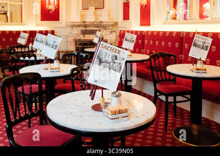 Vienne, Autriche : intérieur de l'élégant Café Sacher, qui abrite l'original Sacher-Torte, avec un décor rouge, des tables en marbre et des menus de journaux. Banque D'Images