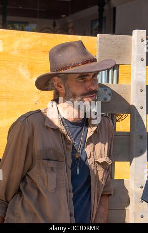 Un homme blanc barbu de 40 ans portant un chapeau de cow-boy se tient à l'arrière d'un lit de camion au Santa Barbara Farmer's Market. Banque D'Images