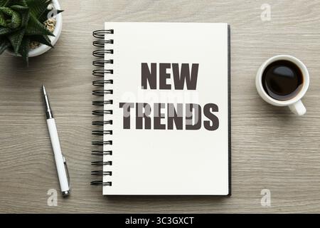 Nouvelles tendances inscription dans le carnet, café et stylo sur la table en bois, vue de dessus Banque D'Images