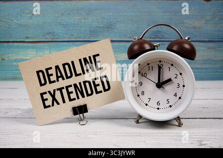 Date limite texte étendu écrit sur carte papier avec réveil sur fond en bois Banque D'Images