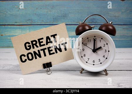 Grand contenu texte écrit sur carte papier avec réveil sur fond en bois Banque D'Images