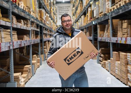 Tallinn, Estonie, 23.09.2023 Ikea, homme avec boîte à plat dans l'allée de l'entrepôt prêt pour l'assemblage à la maison Banque D'Images