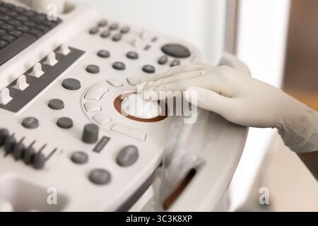 Mains du médecin féminin dans des gants en caoutchouc à l'aide de la machine à ultrasons Banque D'Images