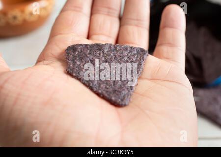 Une vue d'une puce de tortilla de maïs bleue dans la paume de la main. Banque D'Images