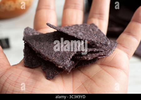 Une vue d'un tas de chips de tortilla de maïs bleu dans la paume de la main. Banque D'Images