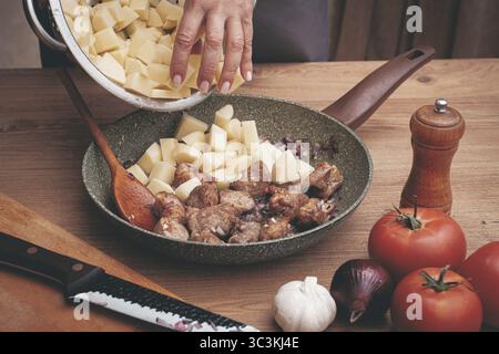 Les tranches de pommes de terre sont disposées dans une poêle, avec de la viande dorée, en cuisant de la viande cuite avec des pommes de terre Banque D'Images