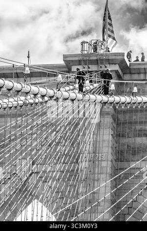 Les policiers de la ville de New York mènent un exercice d'entraînement en angle droit sur les câbles suspendus du pont de Brooklyn à New York. Banque D'Images