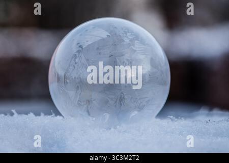 Bulle de savon gelée reposant sur la neige, motif de cristal de glace dans le froid d'hiver avec fond sombre avec espace de copie Banque D'Images