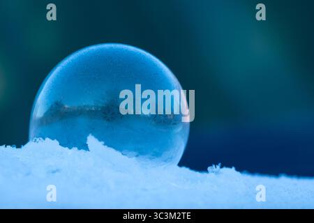 Bulle de savon gelée reposant sur la neige, motif de cristal de glace en hiver avec fond sombre pour l'espace de copie Banque D'Images