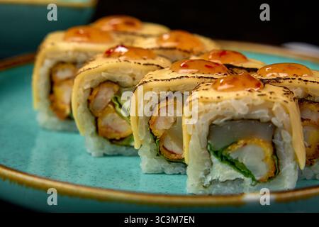 Délicieux Sushi Rolls avec crevettes, avocat et garnitures crémeuses servis sur une assiette vibrante présentant un délice culinaire Banque D'Images
