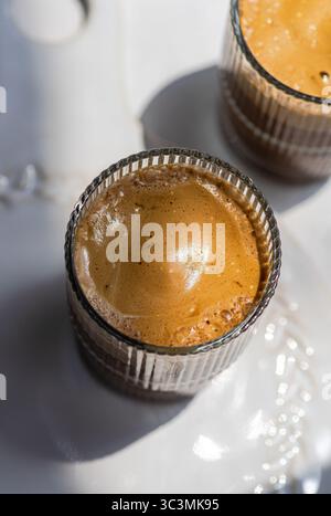 Une vue rapprochée d'un cappuccino froid avec un haut riche et mousseux servi dans un verre clair, capturant la texture invitante et l'arôme séduisant de cette popula Banque D'Images