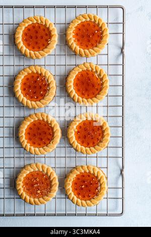 Petits gâteaux fraîchement cuits recouverts de marmelade de cerises sucrées. Parfaitement dorés et faits à la main, ces bonbons sont un régal pour tout amateur de desserts Banque D'Images