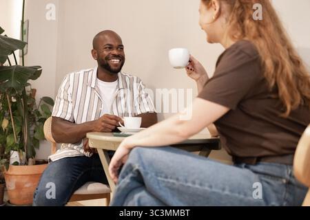 Un moment de détente dans un café écologique où un homme et une femme apprécient le café et la conversation. Entourés d'un décor confortable et de plantes luxuriantes, ils savourent Thi Banque D'Images