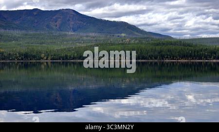 Les eaux vitreuses du lac McDonald reflètent une crête boisée sous des nuages spectaculaires, invitant à l'exploration de la vaste nature sauvage sereine du parc national des glaciers ! ! Banque D'Images