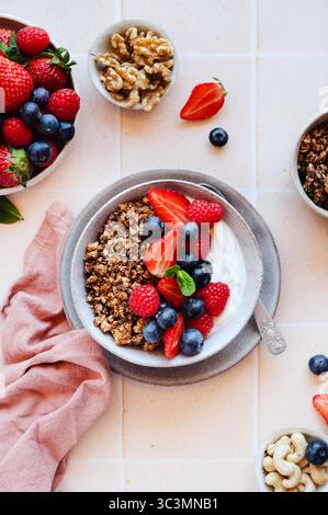 Un délicieux bol de petit déjeuner avec granola croquant avec des baies rouges, des bleuets et du yaourt. Garni de menthe fraîche, ce combin repas nutritif Banque D'Images