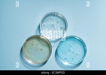 Trois boîtes de Pétri contenant des gels colorés, utilisées dans la recherche et le développement de cosmétiques. L'image met en évidence l'approche scientifique de enhanc Banque D'Images