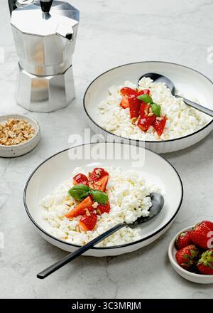 Petit déjeuner délicieux et nutritif composé de fromage cottage crémeux garni de fraises fraîches et juteuses. Idéal pour un début de journée sain, captu Banque D'Images