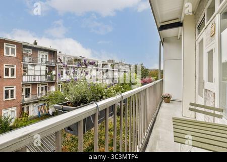 Un balcon serein orné de fleurs en fleurs surplombe un quartier urbain animé, reflétant la beauté de la vie urbaine Banque D'Images