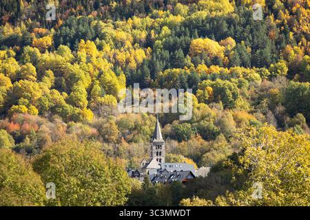 Une scène pittoresque des Pyrénées en automne, avec une charmante église nichée au milieu d'un feuillage vibrant et coloré. Le paysage forestier est riche en esprit Banque D'Images