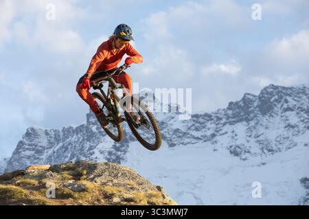 D'en bas, un VTT masculin dans un équipement vibrant navigue habilement dans une descente abrupte dans les superbes Alpes suisses, faisant preuve à nouveau d'un esprit sportif extrême Banque D'Images