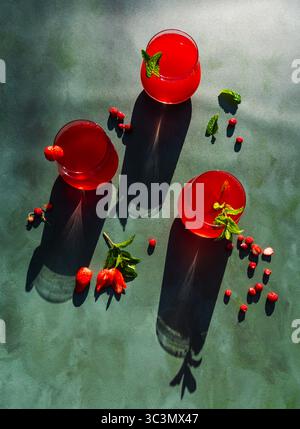 Vue de dessus d'une vue rafraîchissante de thé d'été froid infusé de fraises et d'hibiscus. La boisson rouge vibrante est garnie de menthe fraîche, capturant Banque D'Images