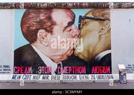 Berlin, Allemagne - 30 mai 2025 : murale vibrante sur le mur de Berlin montre un gros plan de deux dirigeants politiques se serrant des lèvres, symbolisant l'unité et le conflic Banque D'Images