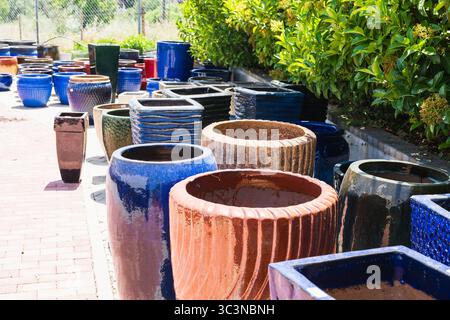 Une collection vibrante de jardinières en céramique émaillée dans les tons bleu, rouge, vert, brun et noir est exposée dans un centre de jardinage. Banque D'Images