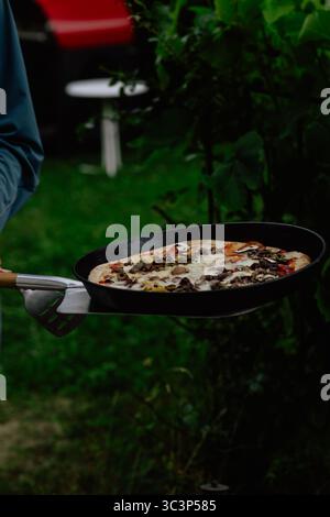 Pizza fraîchement cuite au feu de bois sur un plateau en métal avec fond vert rustique Banque D'Images