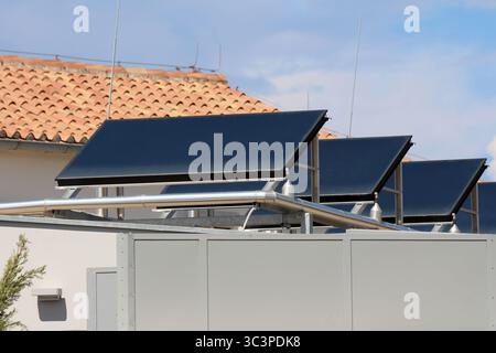 Trois grands capteurs solaires de chauffage de l'eau sont montés sur le toit d'un bâtiment, avec un système de tuyaux en acier inoxydable interconnectés pour la distribution Banque D'Images